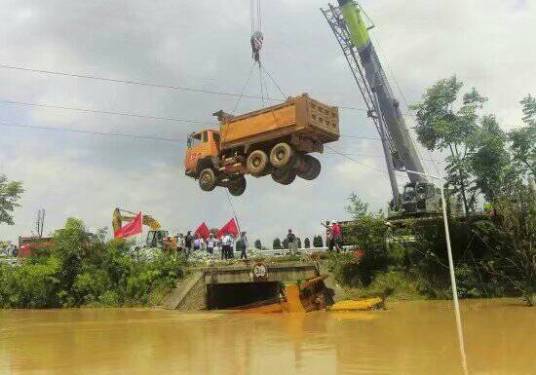 瞬间：抢险队利 用起重机将渣土车吊入水中阻断洪水