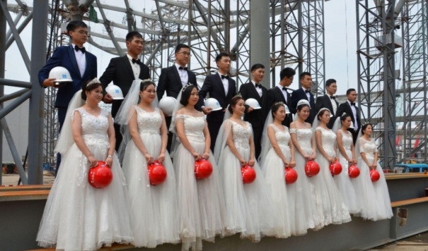昨天，9对新人戴着安全帽在全球最大会展中心工地上举行了婚礼